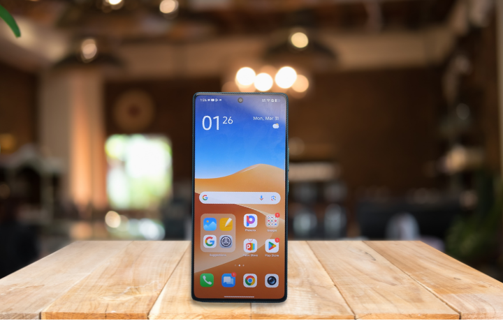 Infinix Note 50 smartphone in green with AMOLED display, dual cameras, and premium alloy frame placed on a wooden table.